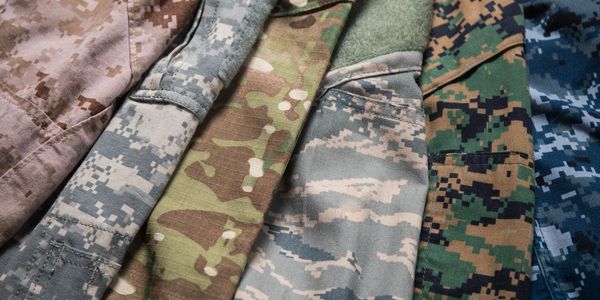 Various military camouflage uniforms arranged side by side.