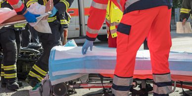 Emergency responders assist an injured person on a stretcher at an accident scene.