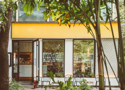 Cozy cafe entrance framed by trees and greenery.