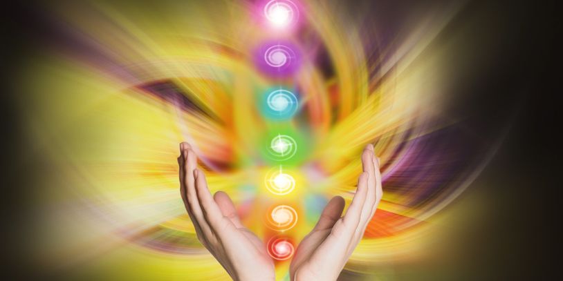 Hands channeling vibrant chakra energy with colorful glowing symbols.