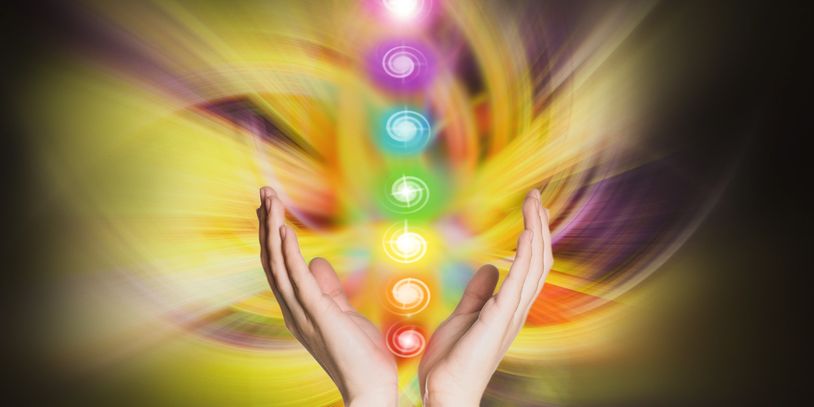 Hands channeling vibrant chakra energy with colorful glowing symbols.