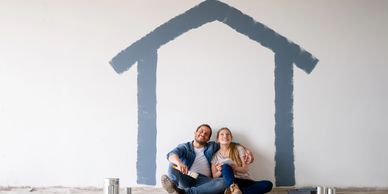 Homeowners sitting in front of a house outline symbolizing insurance savings from a monitored alarm 