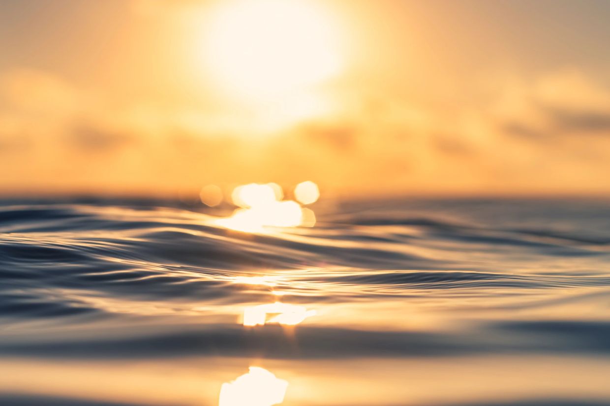 Sunlight reflecting on gentle ocean waves at sunset.