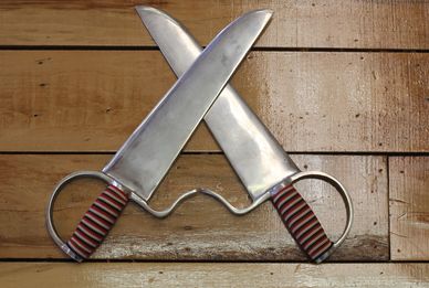 Two crossed metal swords with striped handles on a wooden surface.