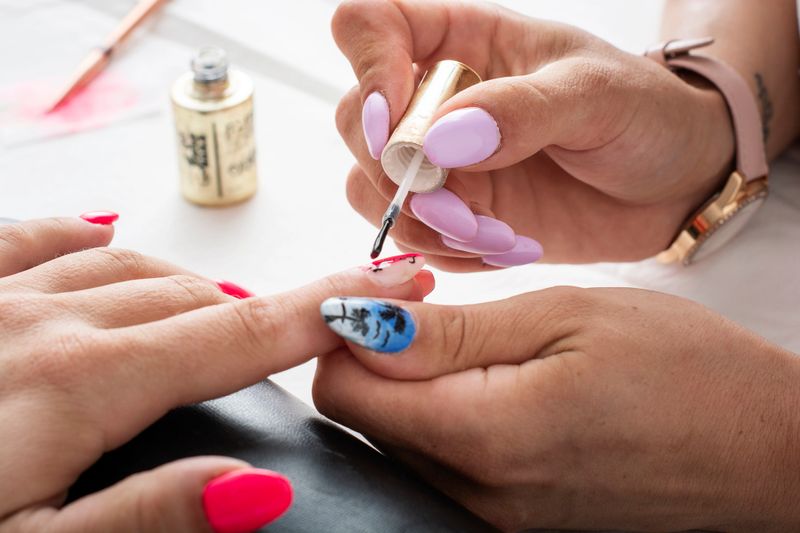 Manicurist painting a woman's fingernails in a beauty center