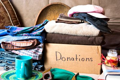 Box labeled 'Donations' with folded clothes and household items around it.