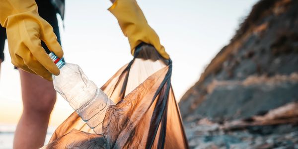 someone partaking in an ocean cleanup by throwing away littered water bottles