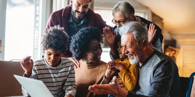 A joyful family with three generations bonding around a laptop.