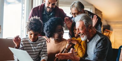 A joyful family with three generations bonding around a laptop.