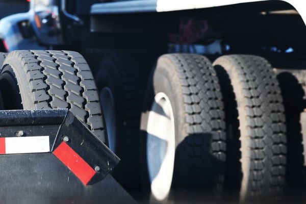 Close-up of heavy-duty truck tires and mudguard with reflective tape.