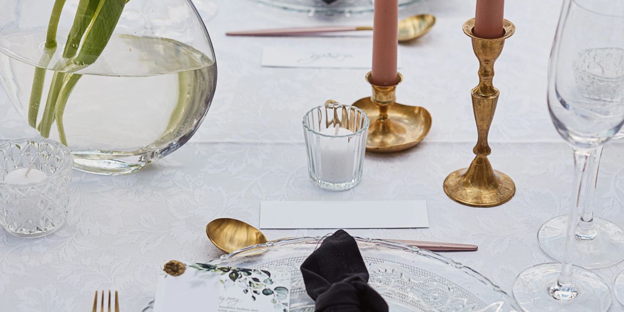 Elegant table setting with gold accents and black napkin on white lace.