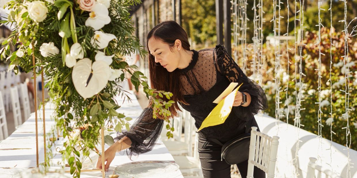 Woman arranging table decorations outdoors.