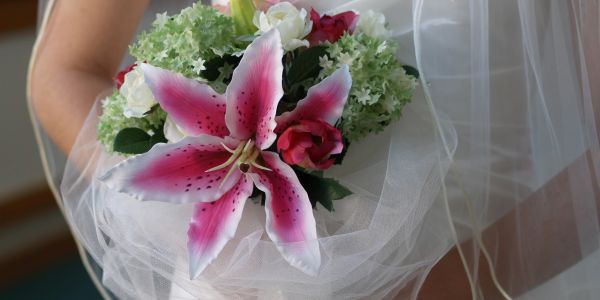 Close-up of a bridal bouquet featuring a pink lily and assorted flowers.