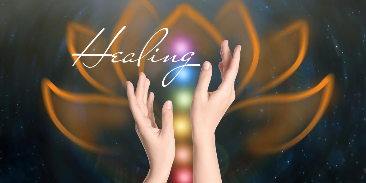 Hands raised in front of a glowing lotus and chakra lights with the word Healing.