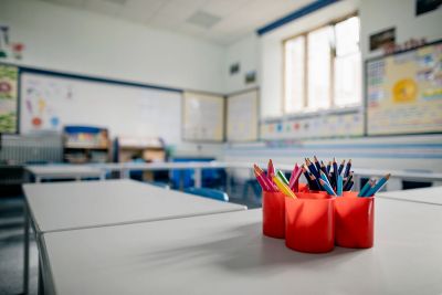 Colored pencils in red holders on a classroom desk.