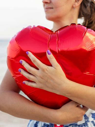 Woman holding a red heart-shaped balloon.