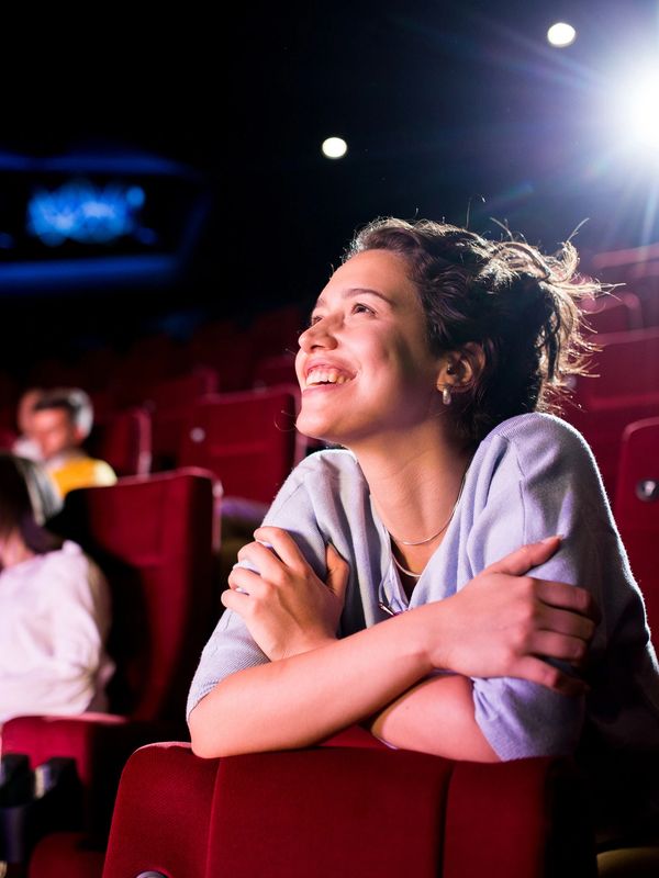 A woman smiling in a movie theater.