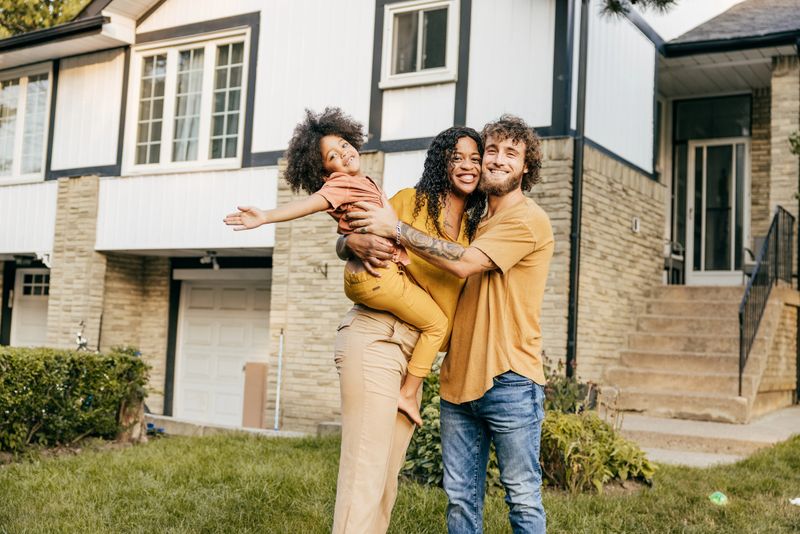 Portrait of multi-ethnical family smiling and looking at camera while standing on their front yard.
