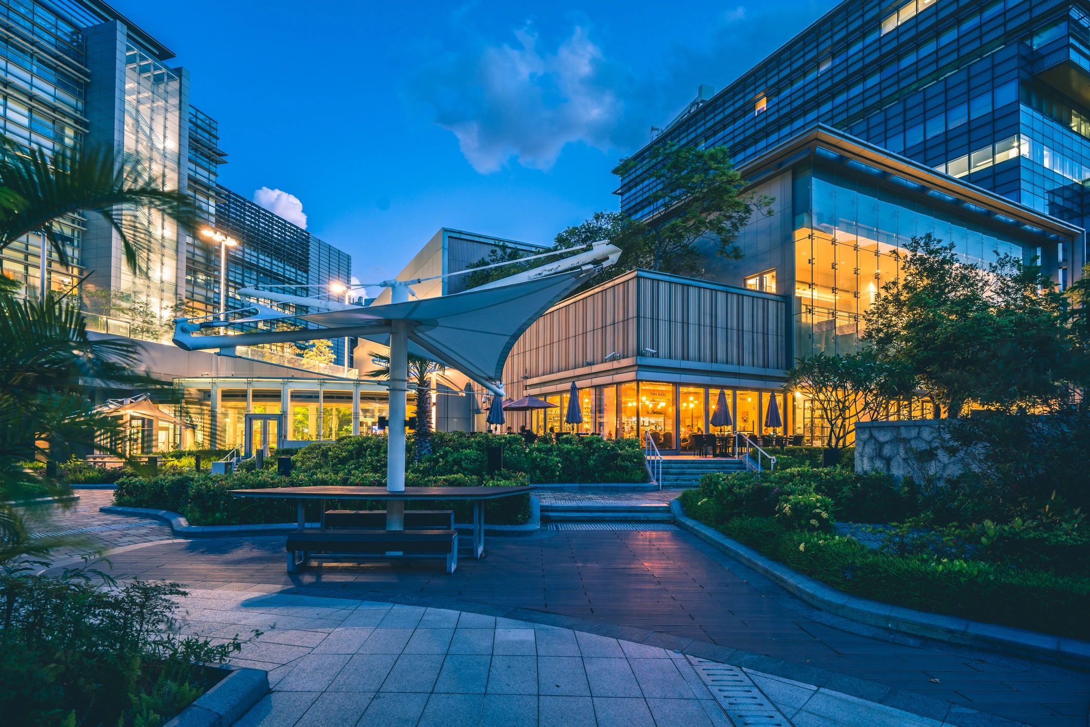 Modern outdoor seating area with illuminated buildings at dusk.