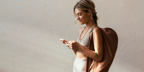 Jeune femme souriante regardant son téléphone avec un sac à dos.