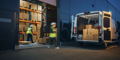 Workers loading boxes into a van at night.