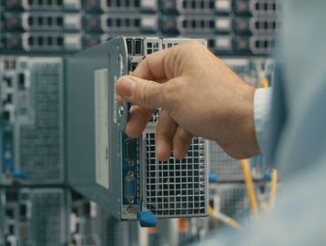Hand inserting or removing a hard drive in a server.