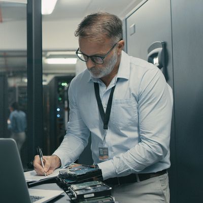 Man working with computer hardware in server room.