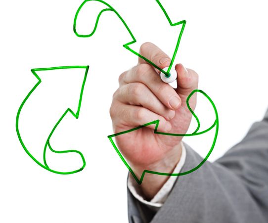 Hand drawing a green recycling symbol on transparent surface.