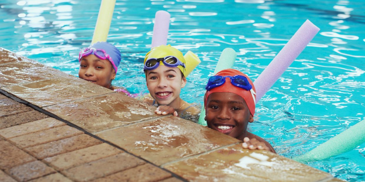 Children swimming in a pool with colorful gear.