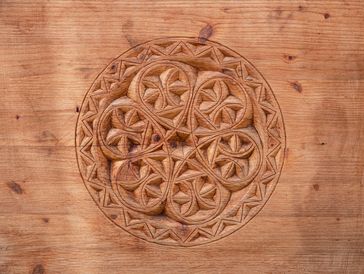 Intricate circular wood carving with geometric patterns.
