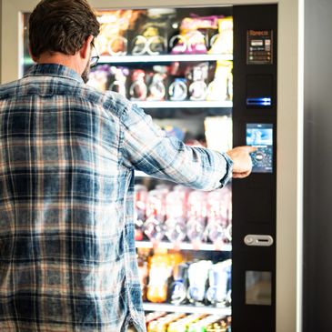 Man selecting a snack from a vending machine with a touchscreen.