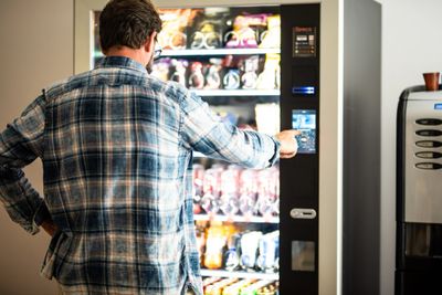A man is standing in front of an open vending machine.