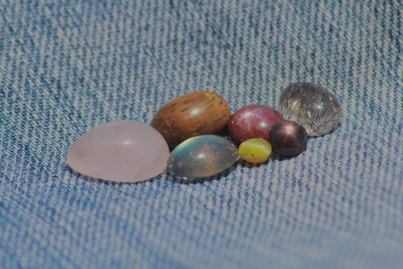 Closeup view of gemstones including star ruby, star sapphire, cats eye, tiger eye, rose quartz, rutile quartz and peacock stone