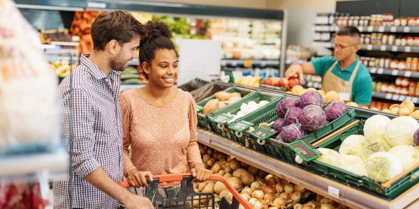 A couple shopping for vegetables in a grocery store.