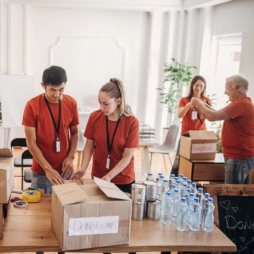 Staff sorting donations and packing boxes in a bright room.