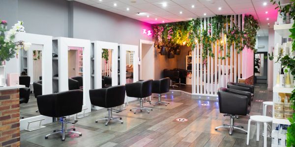 Modern hair salon with black chairs and green plants.