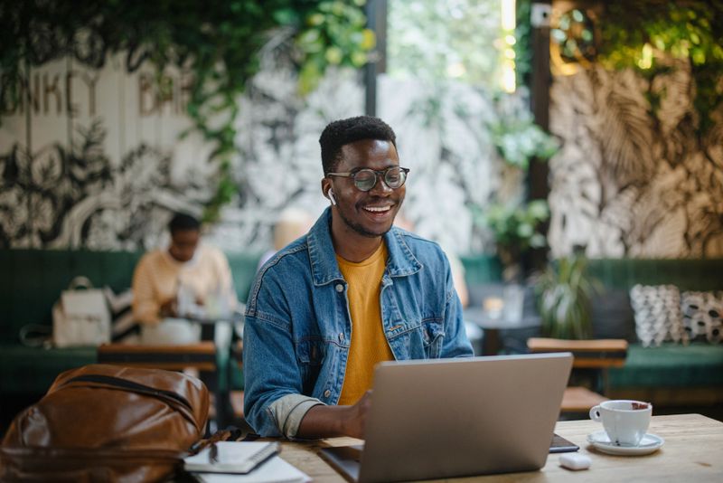 Young black man on a video conference call in a cafe. The concept of online tutoring. The concept of remotely working