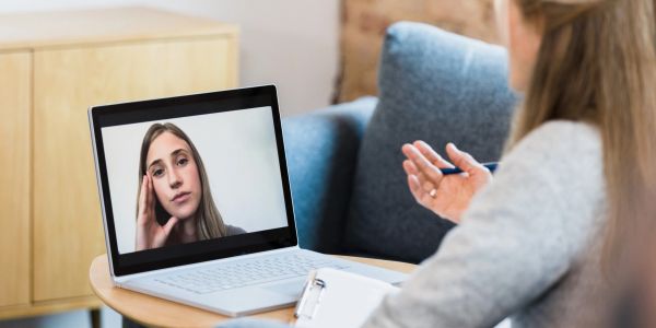Two women engaged in a serious video call on a laptop.