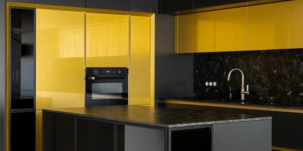 Modern kitchen with bold yellow and black cabinetry and a marble island.