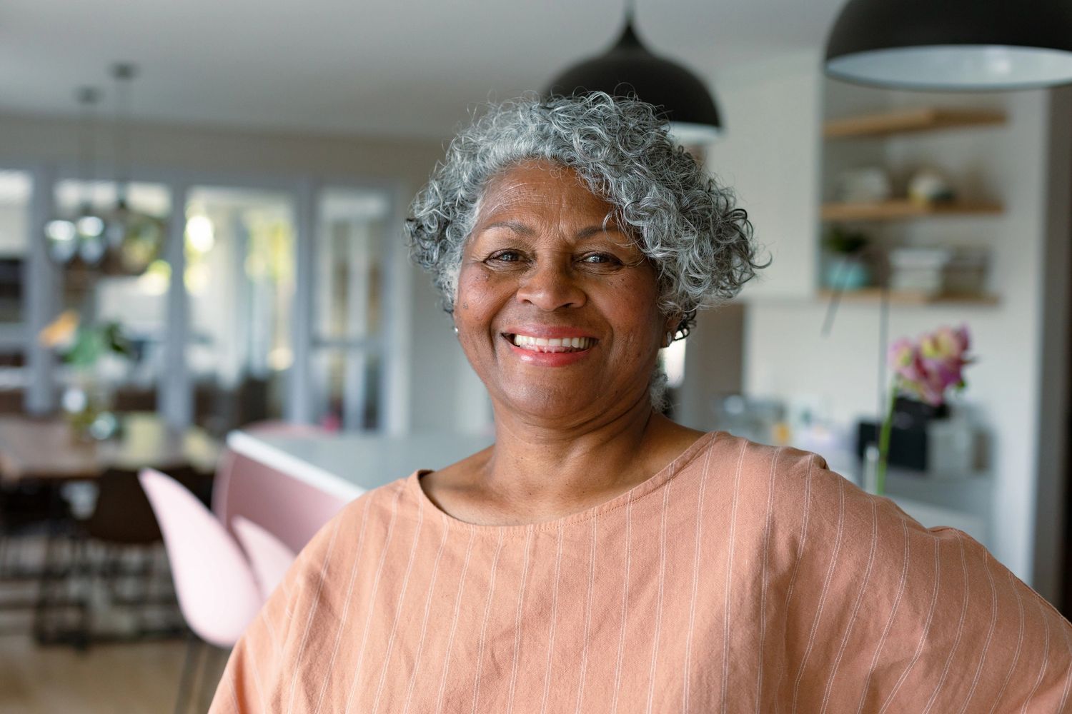 Smiling elderly woman with curly gray hair indoors.