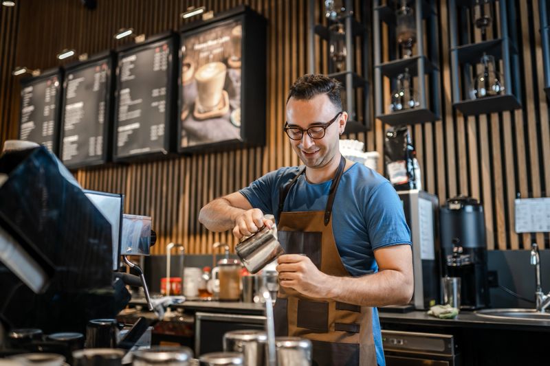 Male barista making coffee for customers at the bar