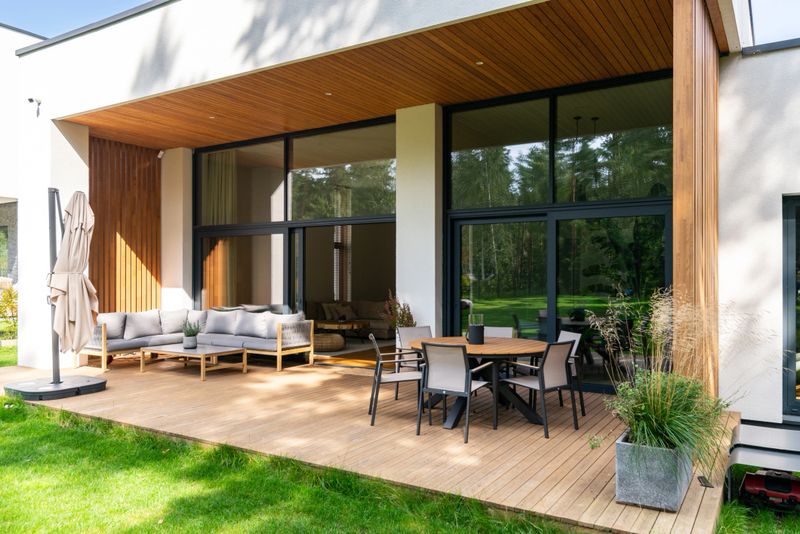 Wooden patio connected to a private building, with seating area and cozy lounge zone.