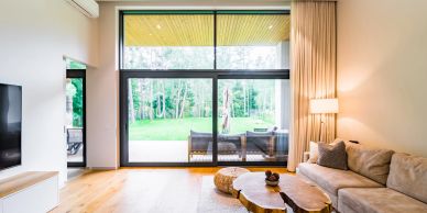 Bright living room with large windows and natural wood furniture.