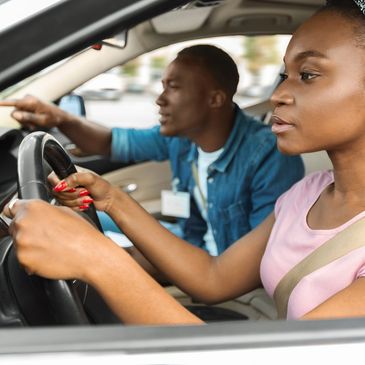 Woman driving car with instructor beside her.