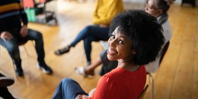 Smiling woman in red shirt sitting in a group meeting.