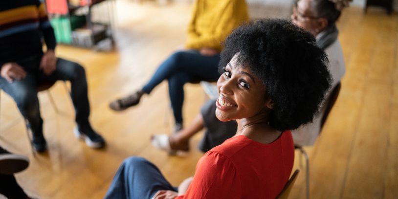 A smiling woman with curly hair in a group setting.
