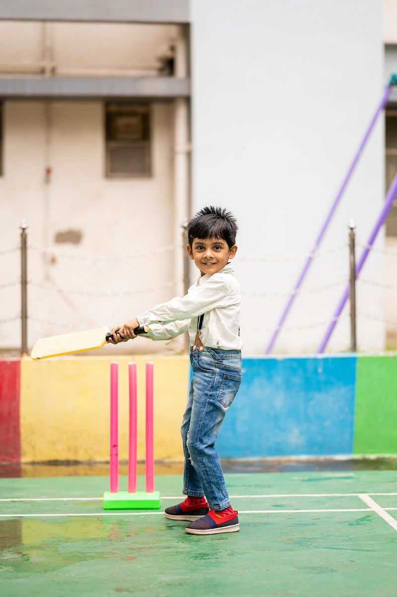 Outdoor image of Cute Indian little child playing cricket at playground.