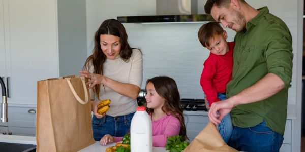 Family unpacking groceries in kitchen.