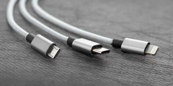 Three different charging cables with USB connectors on a gray surface.