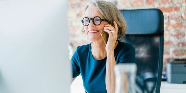 Smiling woman talking on phone at her desk in an office.